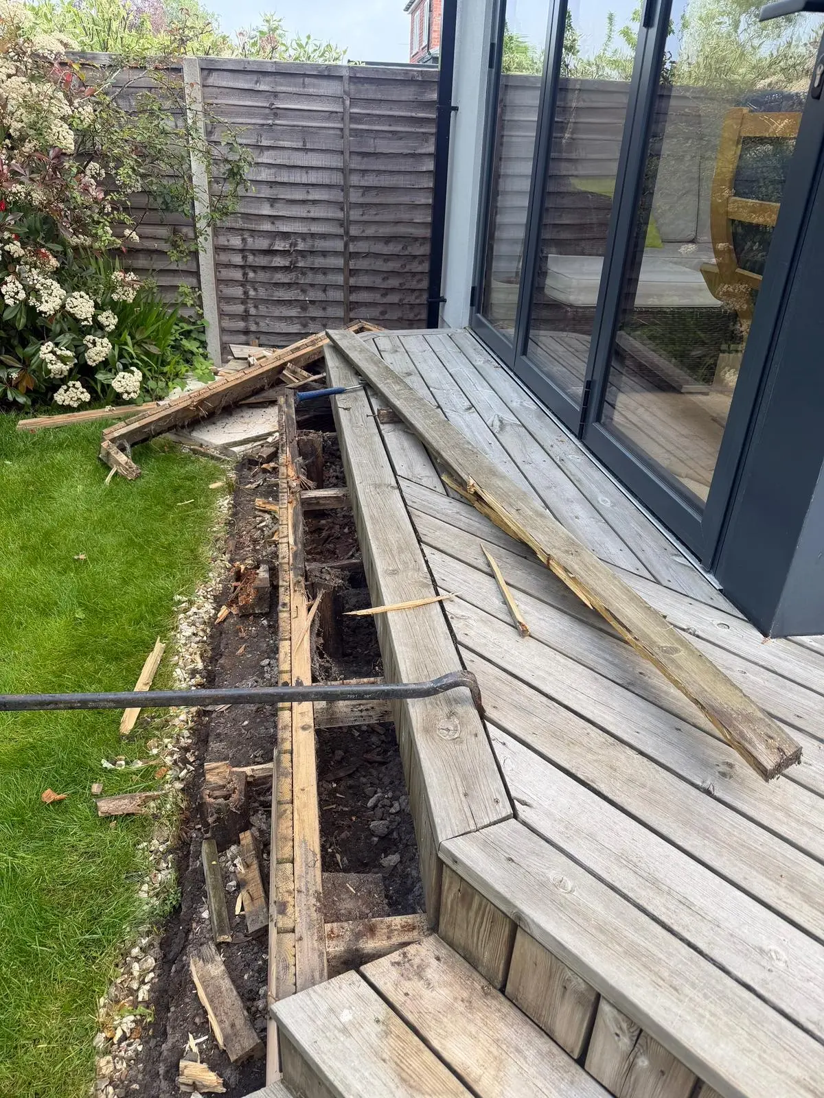 Rotten softwood decking being stripped out, showing decayed joists beneath