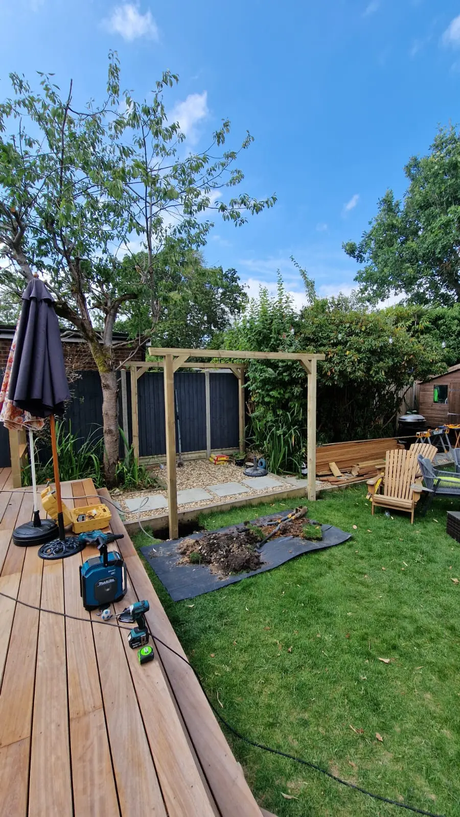 Timber pergola frame standing over a newly laid gravel and paving area