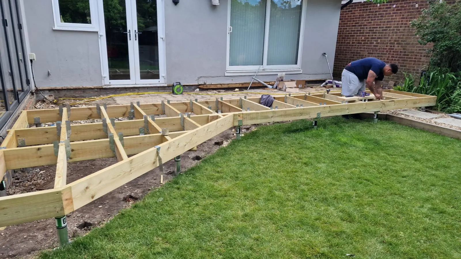 Timber deck substructure set out on ground screws, curving to follow the lawn edge